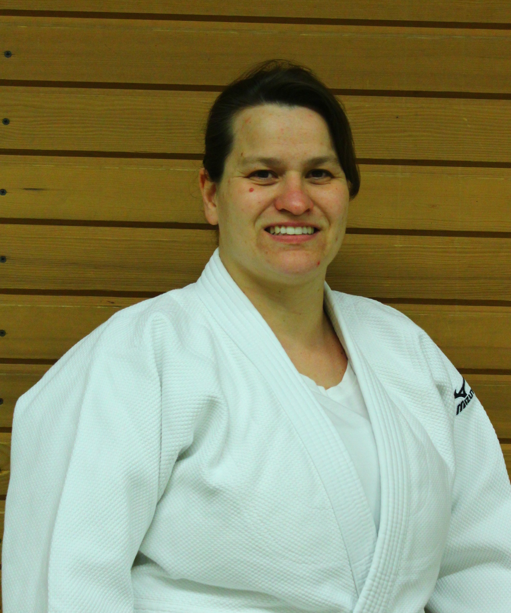 Porträ von Isabell Boxnick, im Judo Anzug vor einer Holzwand.