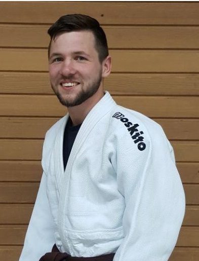 Porträ von Martin Adler, im Judo Anzug vor einer Holzwand.